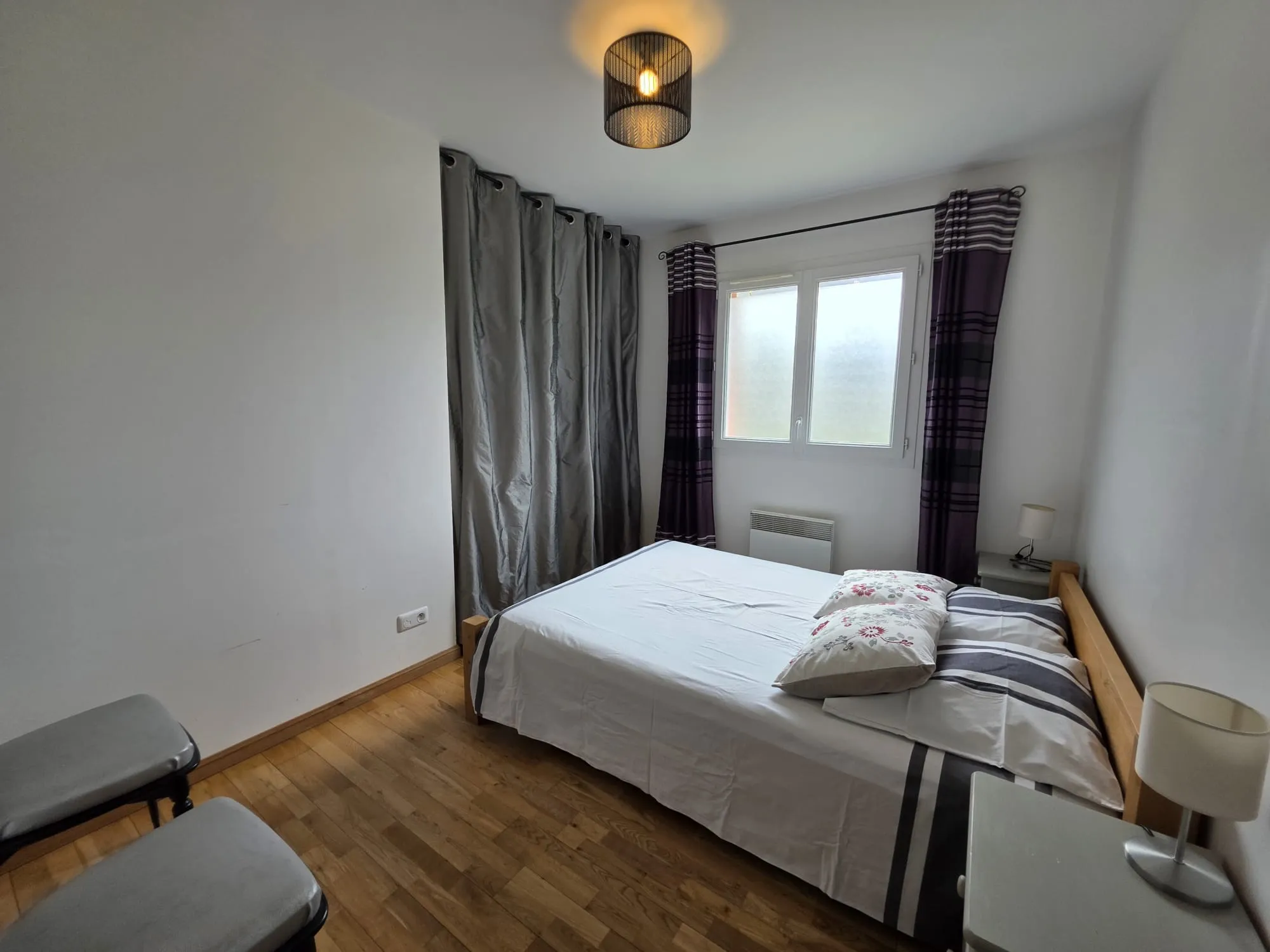 Une chambre avec lit double, parquet et rideaux