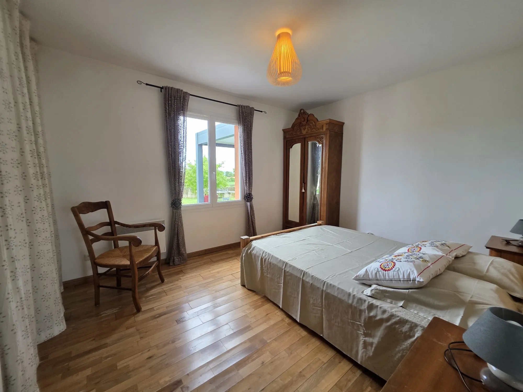 Une chambre avec lit double en bois et armoire ancienne